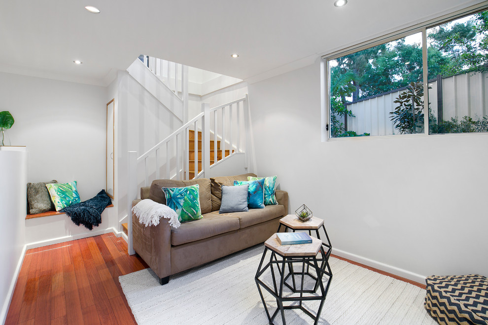 Fernseherloses, Offenes Mid-Century Wohnzimmer ohne Kamin mit weißer Wandfarbe und braunem Holzboden in Sydney