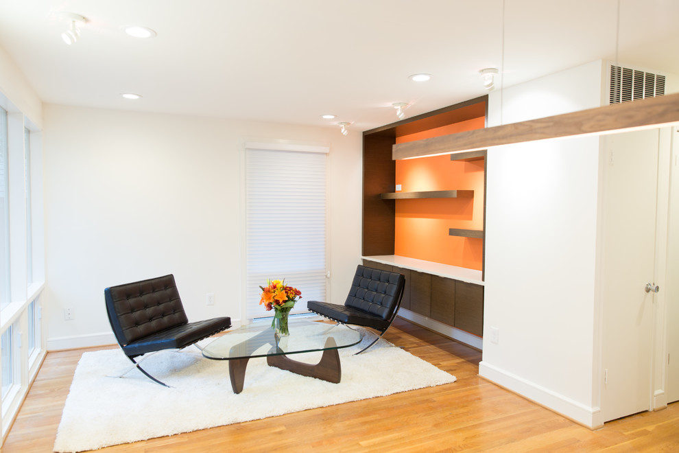 Small modern open plan games room in DC Metro with a reading nook, orange walls and light hardwood flooring.