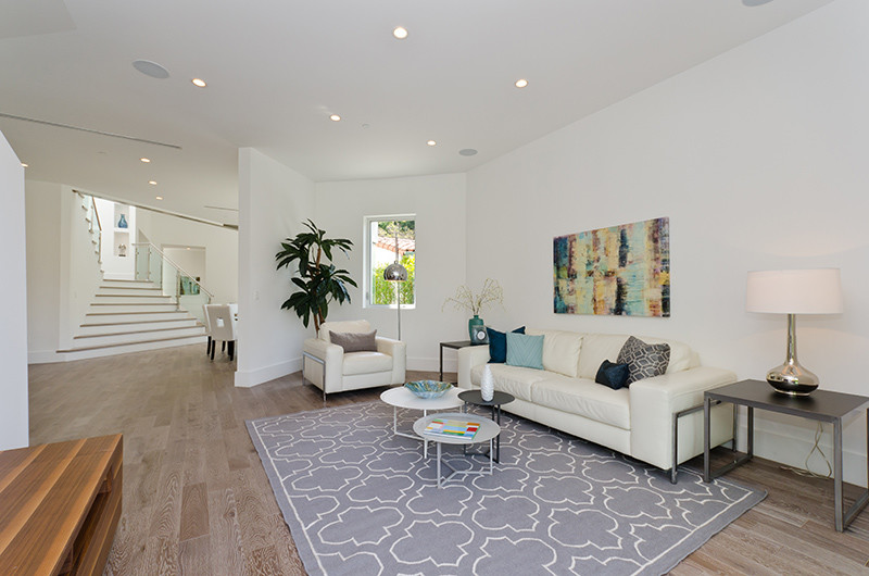 Immagine di un soggiorno minimalista di medie dimensioni e aperto con pareti bianche, parquet chiaro, nessun camino e pavimento beige