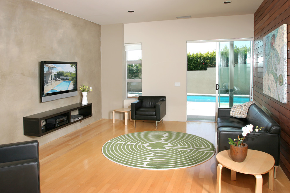 Example of a trendy medium tone wood floor family room design in Orange County with beige walls and a wall-mounted tv
