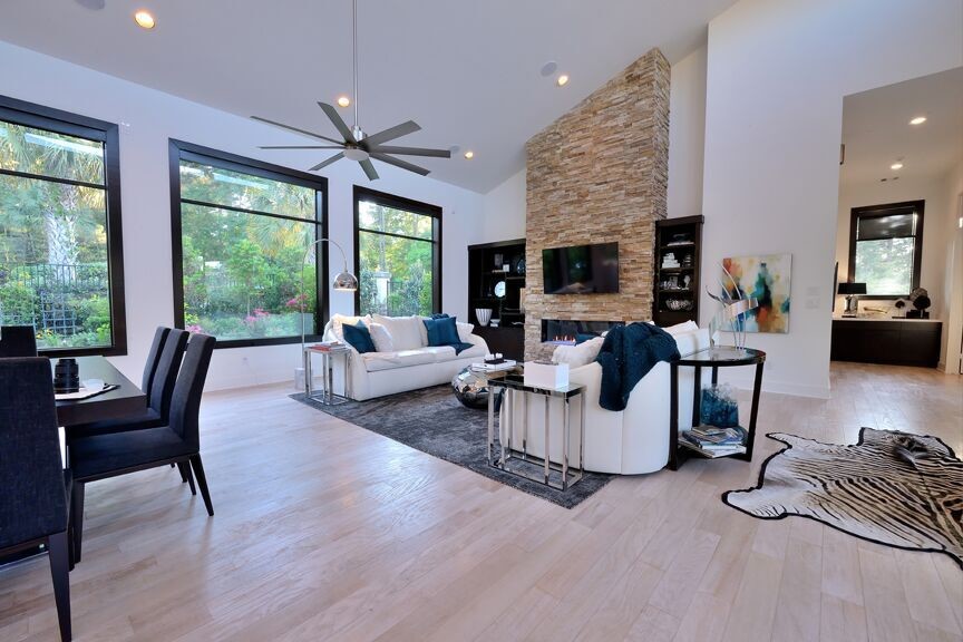 Mittelgroßes, Offenes Modernes Wohnzimmer mit weißer Wandfarbe, Bambusparkett, Kamin, Kaminumrandung aus Stein und TV-Wand in Houston