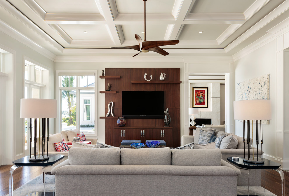 Modelo de sala de estar clásica renovada con paredes blancas, suelo de madera oscura, televisor colgado en la pared y suelo marrón