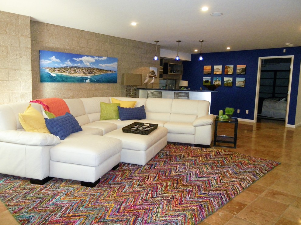 Modelo de sala de juegos en casa abierta minimalista grande sin chimenea con paredes azules, suelo de travertino y pared multimedia