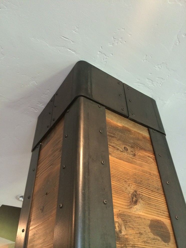 ポートランドにある高級な広いインダストリアルスタイルのおしゃれなオープンリビング (壁掛け型テレビ、グレーの壁、濃色無垢フローリング、標準型暖炉、金属の暖炉まわり) の写真