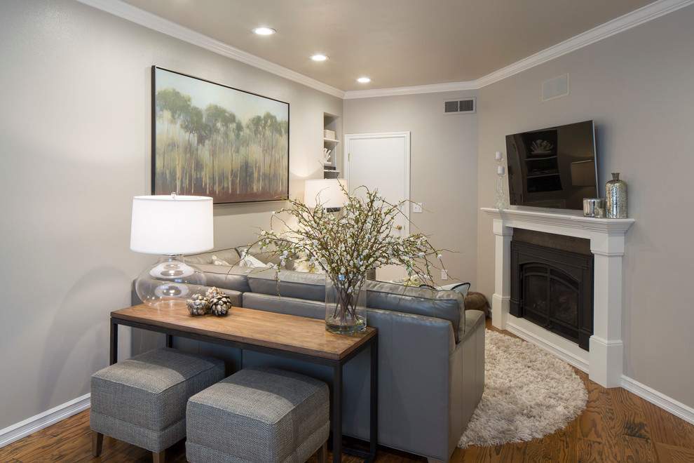 Immagine di un piccolo soggiorno moderno chiuso con pareti grigie, pavimento in legno massello medio, camino classico e TV a parete