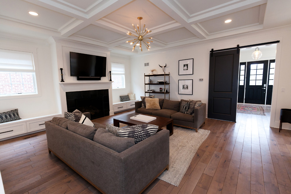 Ejemplo de sala de estar abierta tradicional renovada grande con paredes blancas, suelo de madera en tonos medios, todas las chimeneas, marco de chimenea de madera, televisor colgado en la pared y suelo marrón