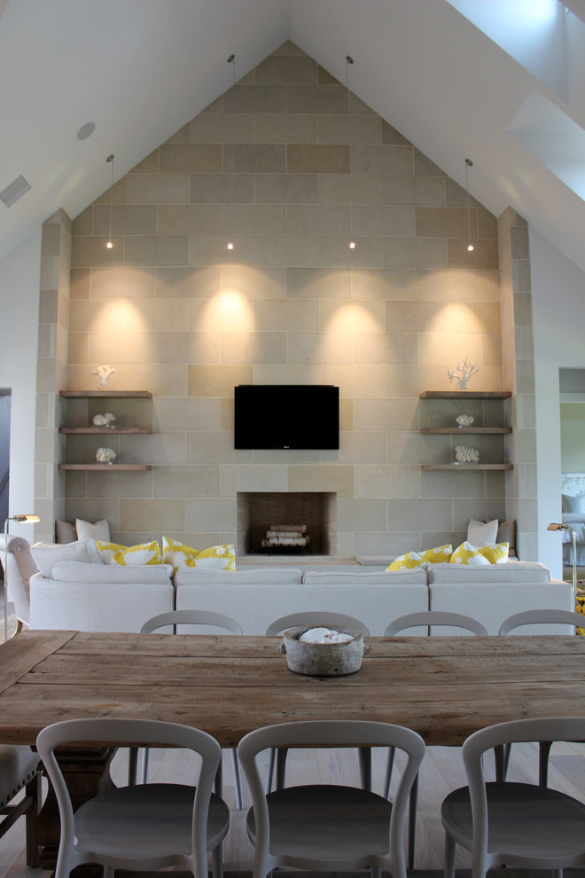 Cette photo montre une salle de séjour chic ouverte avec un mur beige, une cheminée standard, un manteau de cheminée en pierre et un téléviseur fixé au mur.