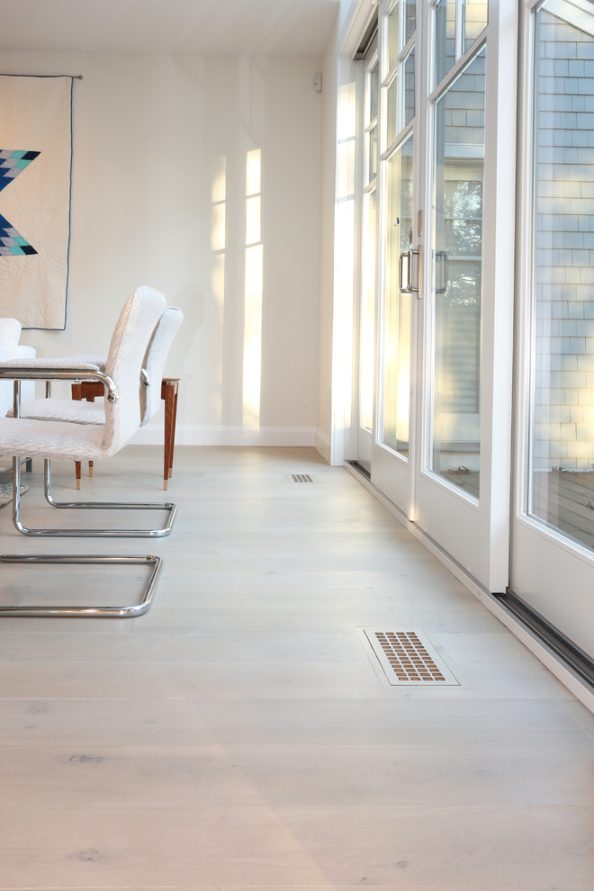 Imagen de sala de estar abierta minimalista de tamaño medio sin televisor con paredes blancas, suelo de madera clara, marco de chimenea de ladrillo y suelo gris