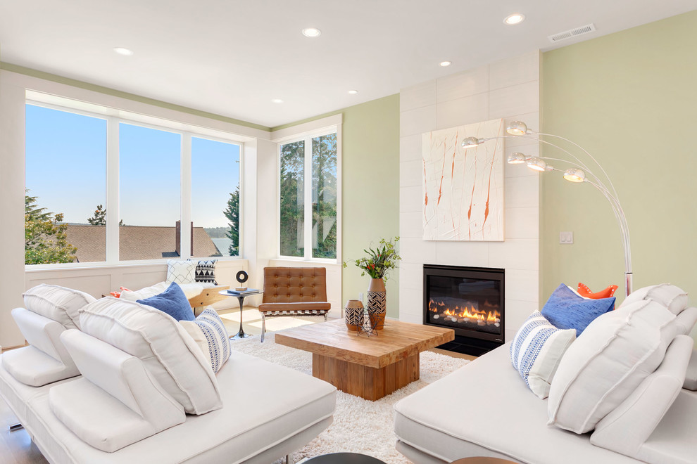 Exemple d'une grande salle de séjour moderne ouverte avec un mur vert, parquet clair, une cheminée standard et un manteau de cheminée en pierre.