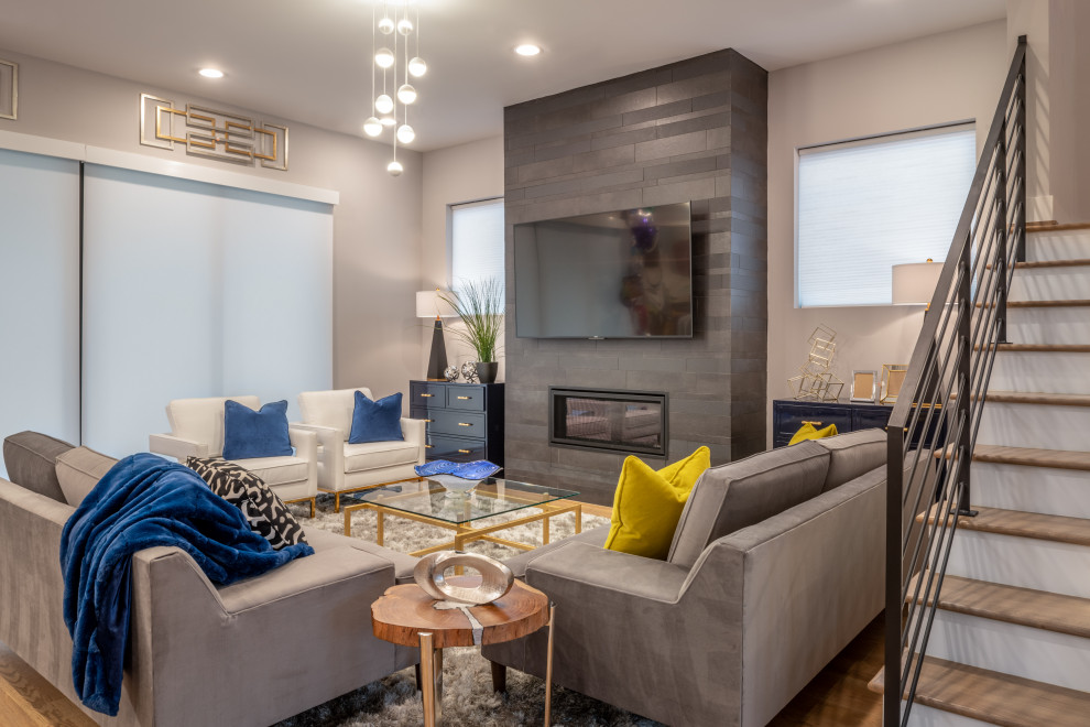 Ejemplo de sala de estar abierta tradicional renovada de tamaño medio con paredes grises, marco de chimenea de baldosas y/o azulejos, televisor colgado en la pared y chimenea lineal