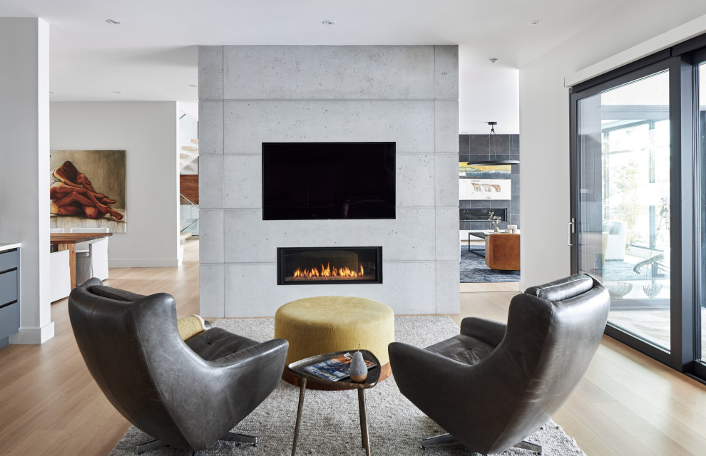 Imagen de sala de estar abierta contemporánea pequeña con suelo de madera clara, chimenea lineal, marco de chimenea de hormigón y pared multimedia