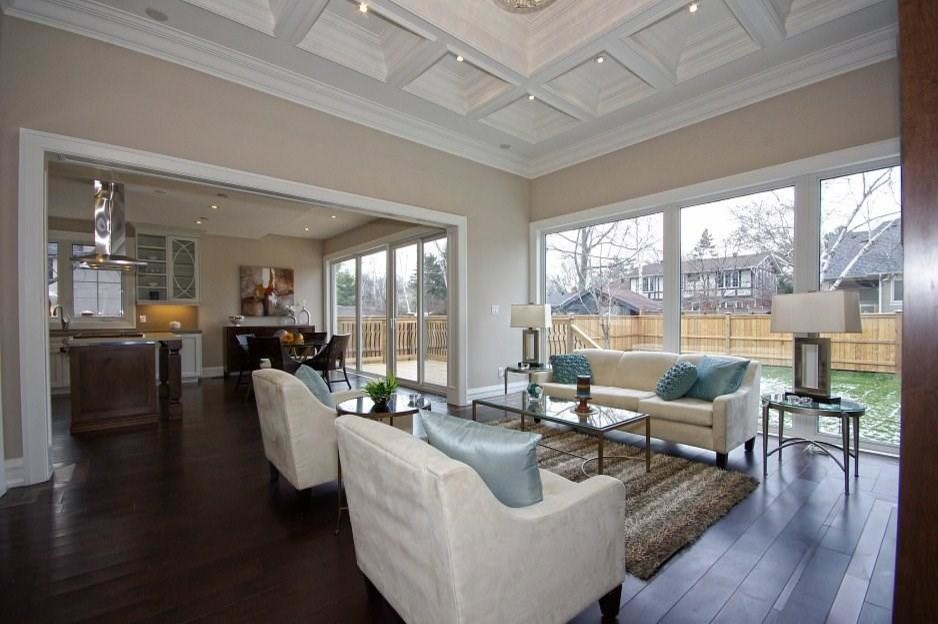 This is an example of a large classic open plan games room in Toronto with beige walls, dark hardwood flooring, a standard fireplace, a wooden fireplace surround, a built-in media unit and brown floors.