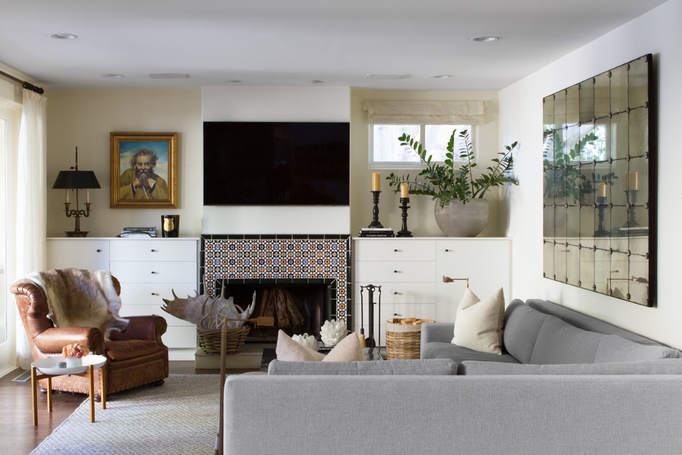 Пример оригинального дизайна: большая изолированная гостиная комната в стиле неоклассика (современная классика) с темным паркетным полом, стандартным камином, фасадом камина из плитки, телевизором на стене, коричневым полом, белыми стенами и ковром на полу