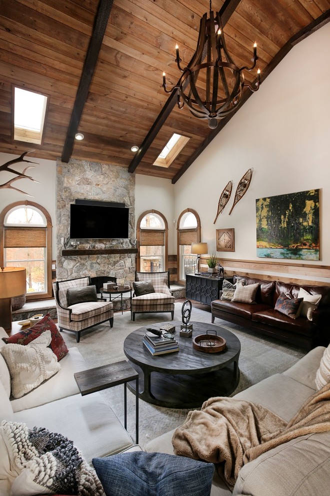 Inspiration for an expansive rustic open plan games room in New York with beige walls, a standard fireplace, a stone fireplace surround and a wall mounted tv.
