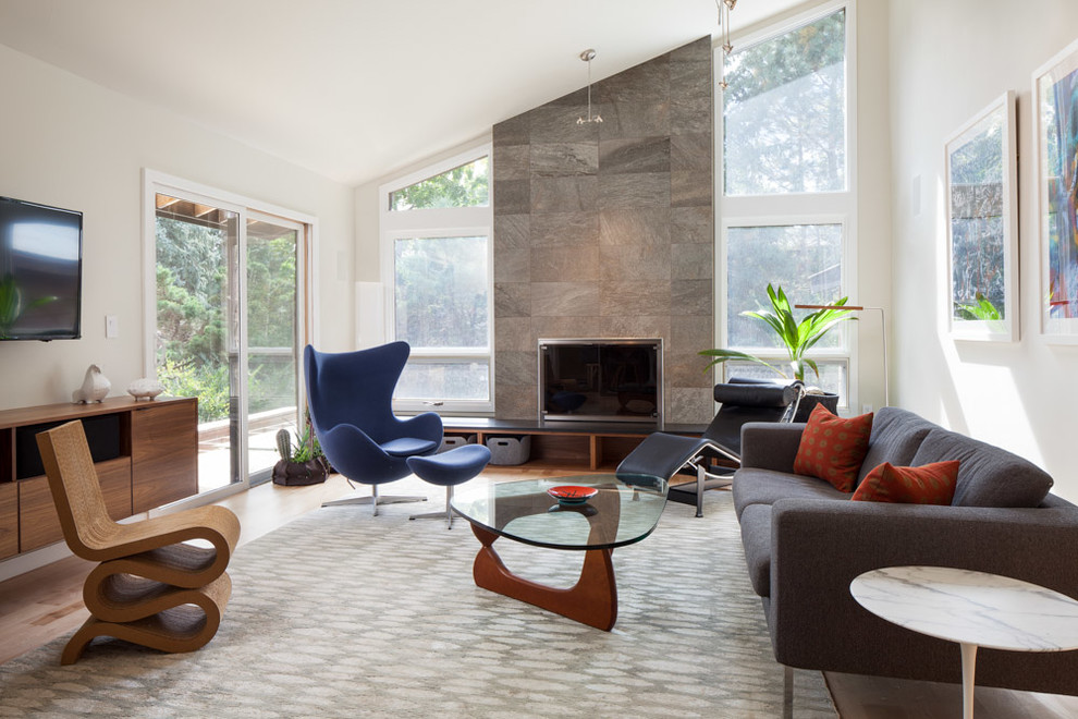 Example of a mid-sized minimalist enclosed light wood floor and beige floor family room design in Denver with white walls, a standard fireplace, a concrete fireplace and a wall-mounted tv