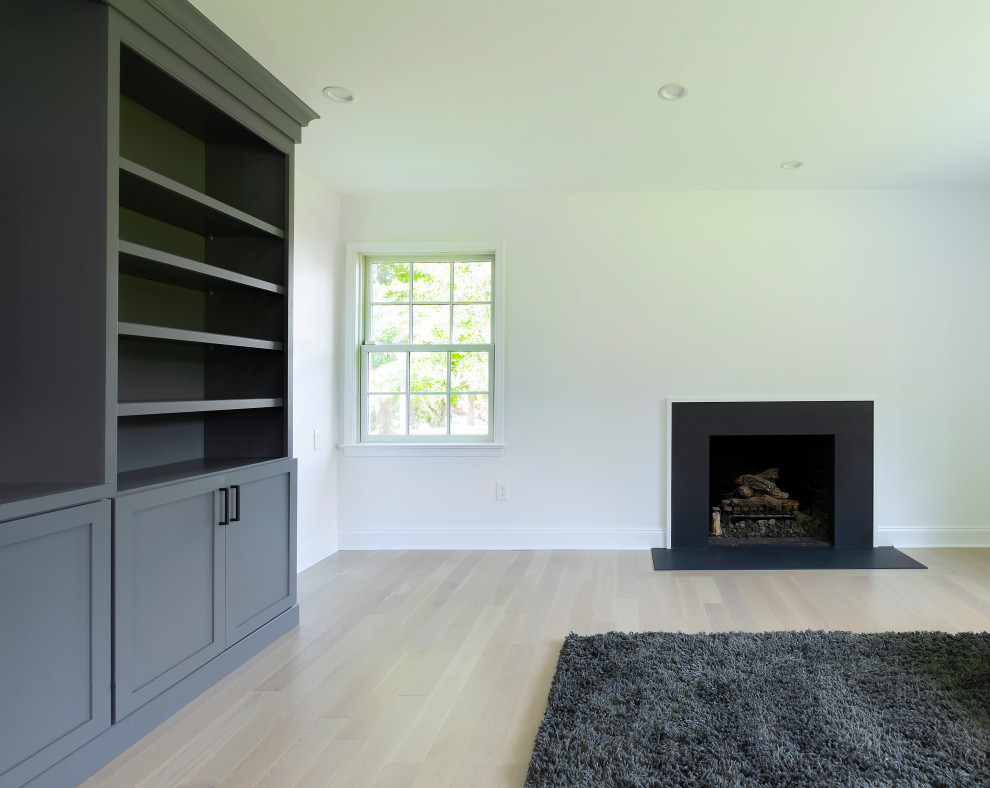 Imagen de sala de estar abierta minimalista de tamaño medio con paredes blancas, suelo de madera clara, todas las chimeneas, pared multimedia y suelo marrón