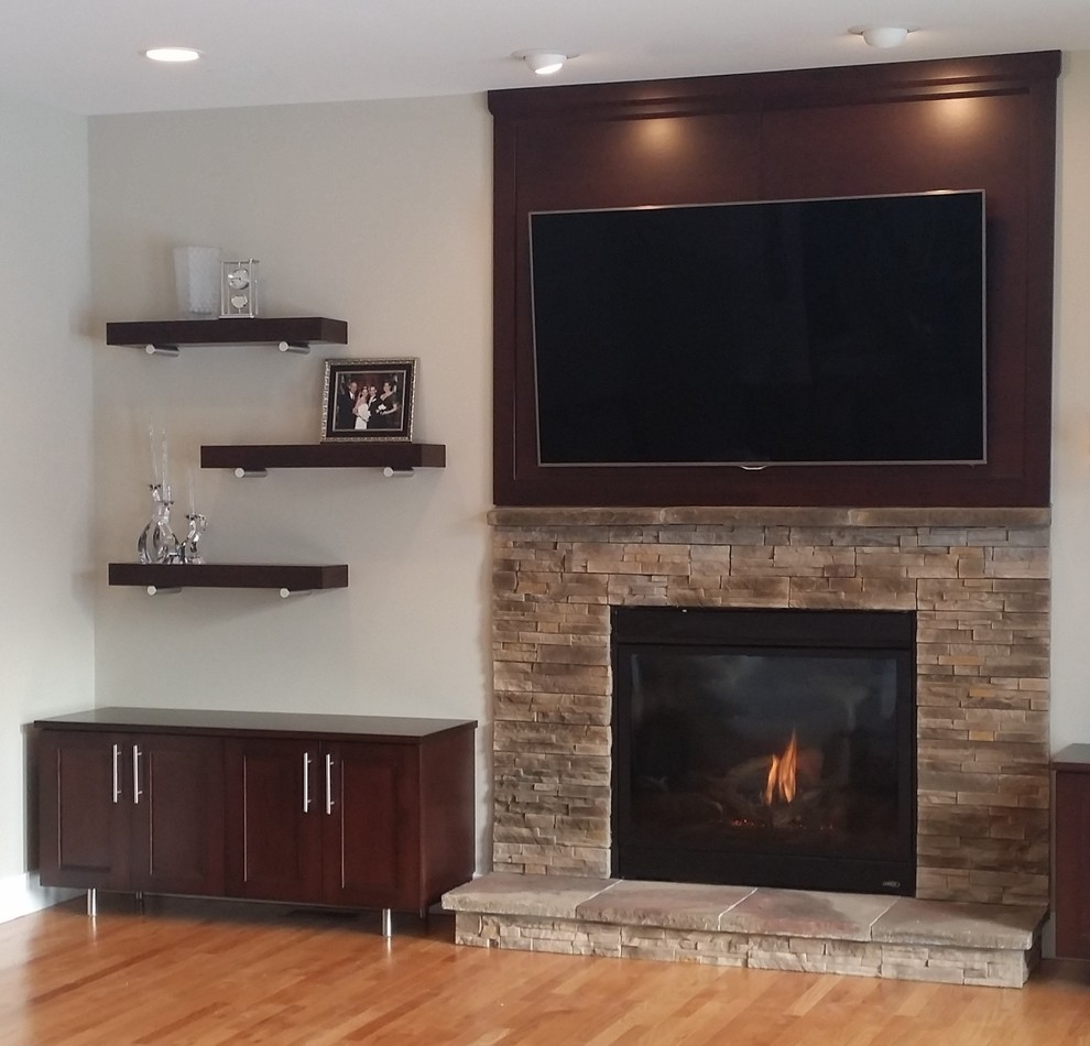 Large modern open plan games room in New York with beige walls, medium hardwood flooring, a standard fireplace, a stone fireplace surround and a wall mounted tv.
