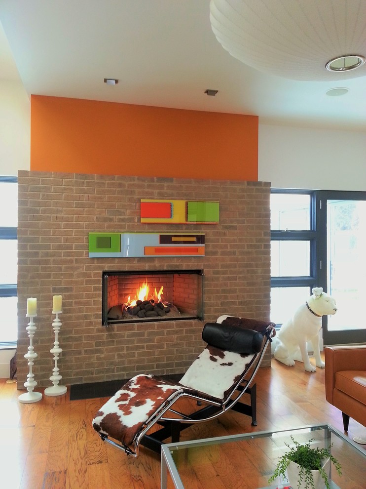 Ispirazione per un grande soggiorno minimalista stile loft con pareti arancioni, pavimento in legno massello medio, camino lineare Ribbon, cornice del camino in mattoni e TV a parete