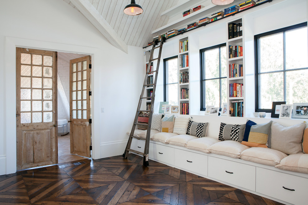 Modelo de sala de estar con biblioteca cerrada de estilo de casa de campo con paredes blancas y suelo de madera oscura