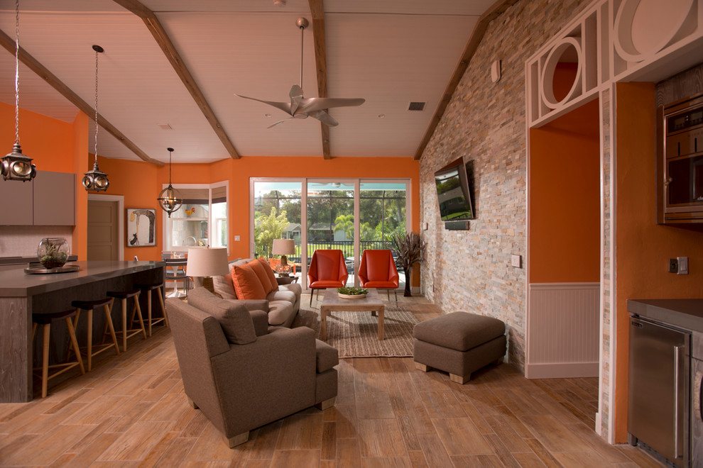 Inredning av ett modernt allrum med öppen planlösning, med orange väggar, klinkergolv i porslin och en väggmonterad TV