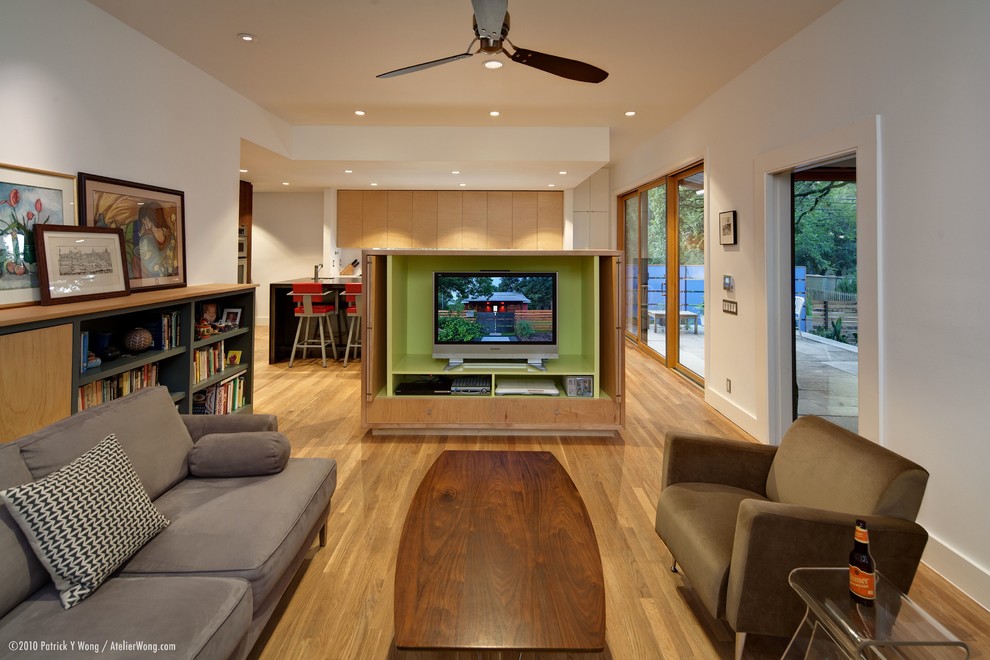 Foto de sala de estar abierta actual con paredes blancas, suelo de madera en tonos medios y pared multimedia