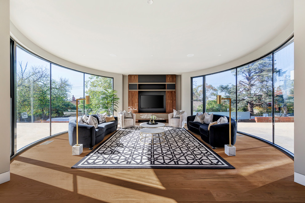 Immagine di un soggiorno moderno chiuso con pareti bianche, pavimento in legno massello medio, TV a parete e pavimento marrone