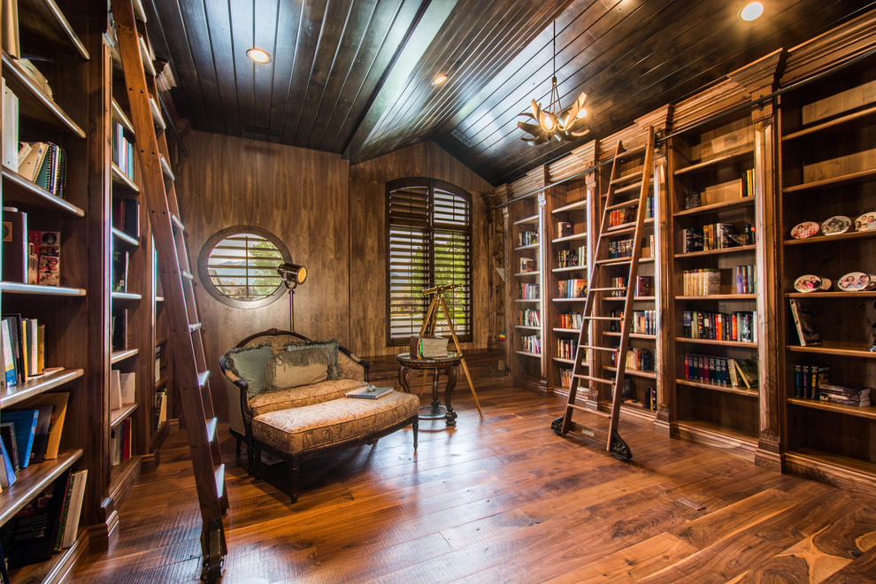 Immagine di un soggiorno tradizionale con libreria, pavimento in legno massello medio, nessun camino e nessuna TV