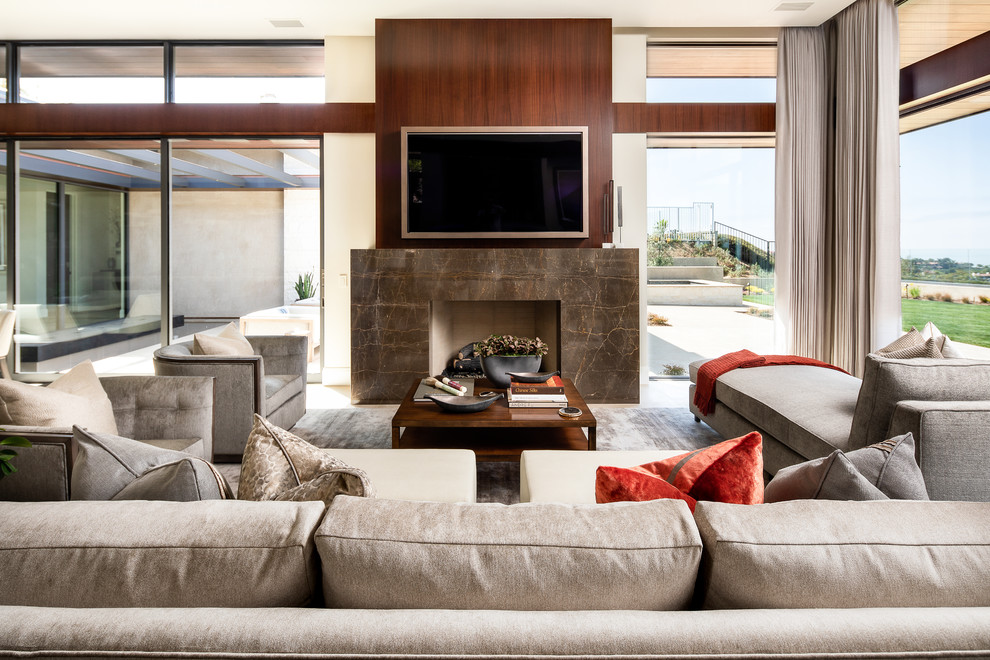 Imagen de sala de estar abierta contemporánea con todas las chimeneas, marco de chimenea de piedra y televisor colgado en la pared