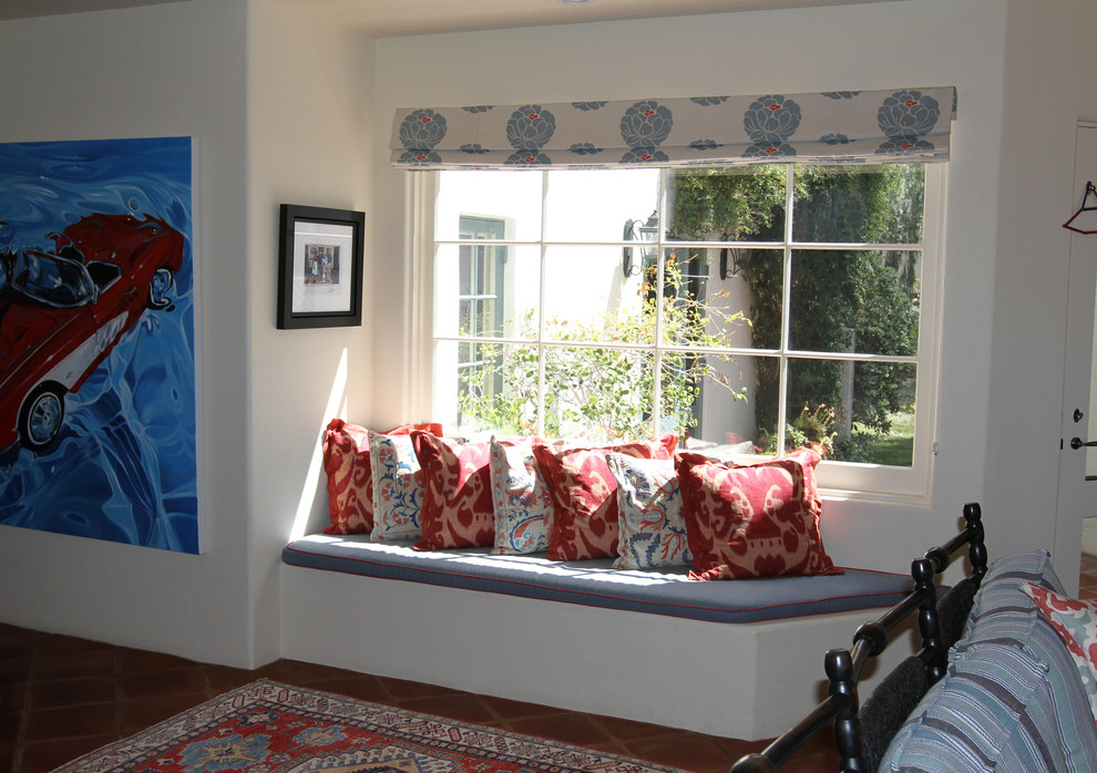 Imagen de sala de estar abierta mediterránea de tamaño medio con paredes beige, suelo de baldosas de terracota, chimenea de esquina, marco de chimenea de baldosas y/o azulejos y televisor colgado en la pared