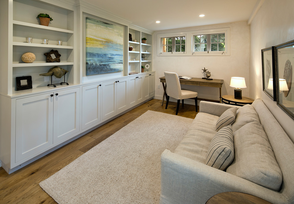 Imagen de sala de estar con biblioteca cerrada romántica con paredes blancas, suelo de madera clara y pared multimedia