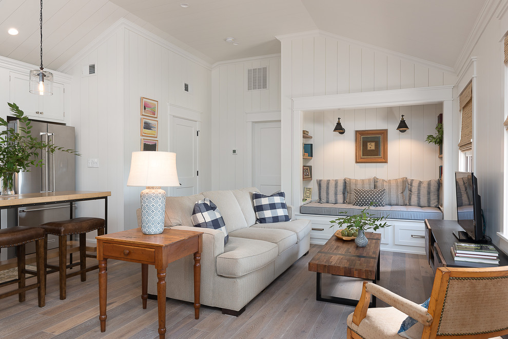 Foto de sala de estar abierta de estilo de casa de campo de tamaño medio sin chimenea con paredes blancas, suelo de madera en tonos medios, televisor independiente y suelo marrón