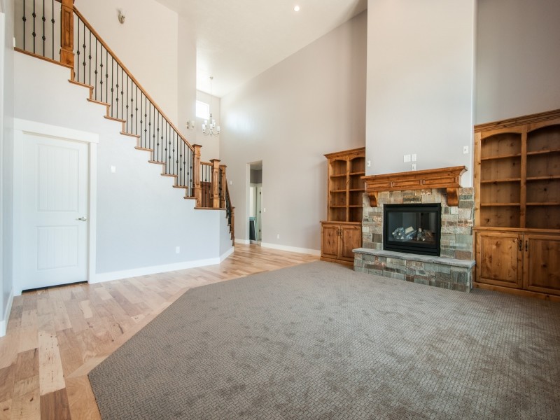 Imagen de sala de estar abierta de estilo americano grande con paredes grises, moqueta, todas las chimeneas y marco de chimenea de piedra