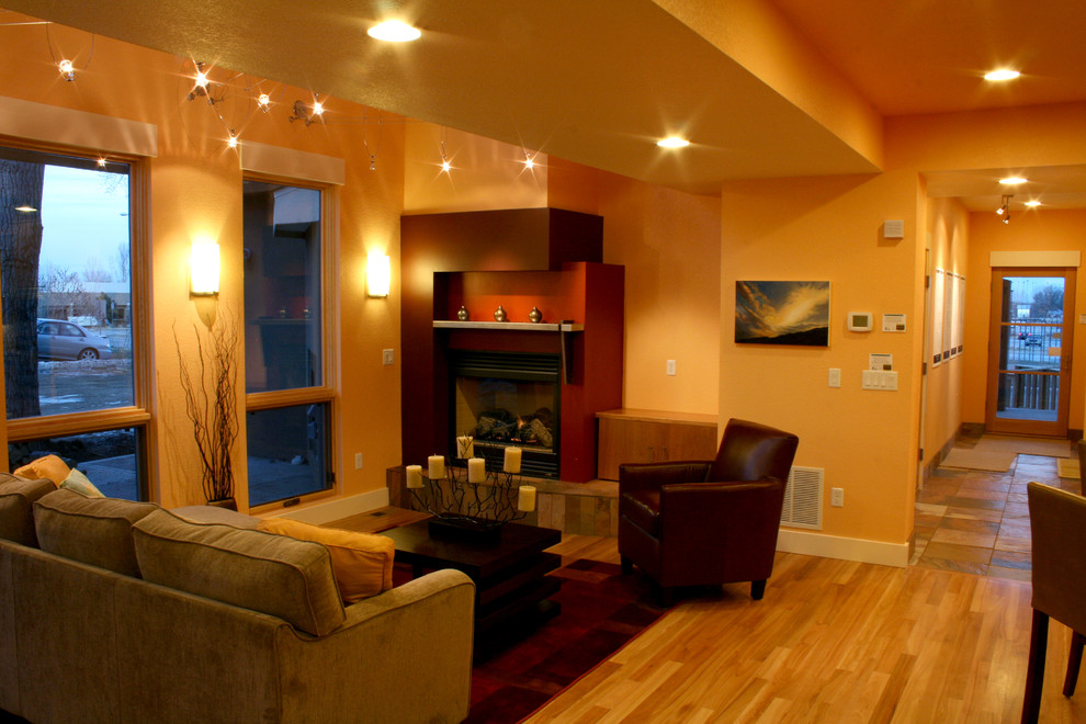 Modelo de sala de estar abierta actual sin televisor con parades naranjas, suelo de madera en tonos medios y todas las chimeneas