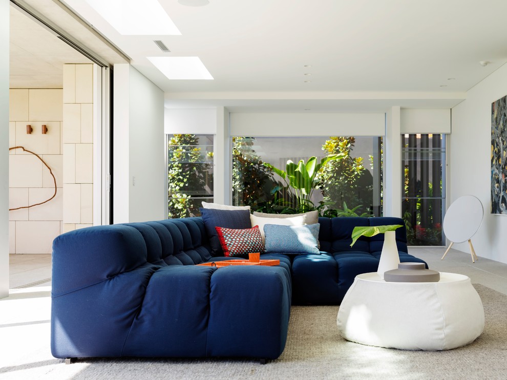 Réalisation d'une salle de séjour design ouverte avec un mur blanc et un sol beige.