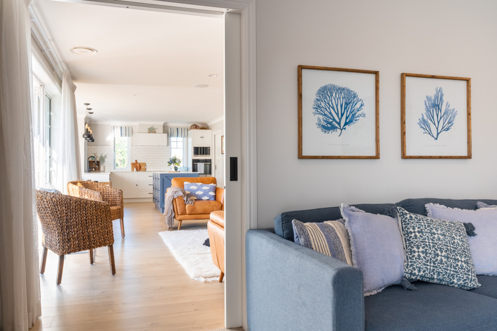 Foto de sala de estar abierta costera de tamaño medio con paredes beige, suelo laminado y suelo beige