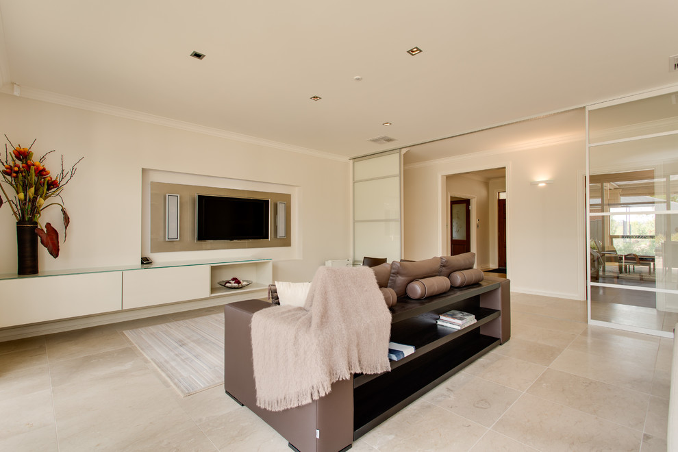 Exemple d'une grande salle de séjour moderne ouverte avec un mur beige, un sol en travertin et un téléviseur fixé au mur.