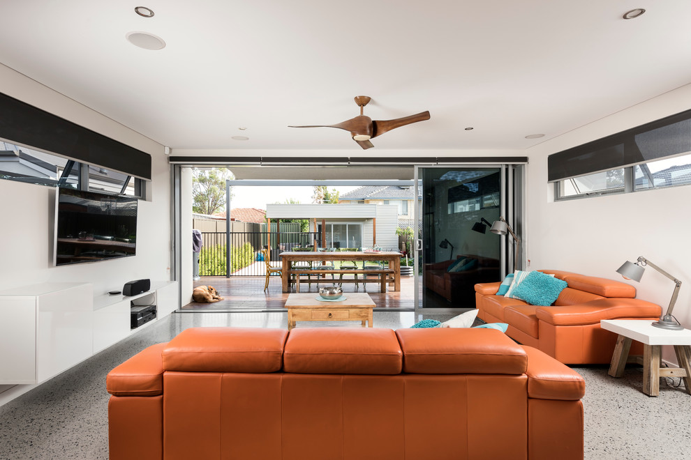 Diseño de sala de estar abierta contemporánea de tamaño medio sin chimenea con paredes blancas, suelo de cemento y televisor colgado en la pared