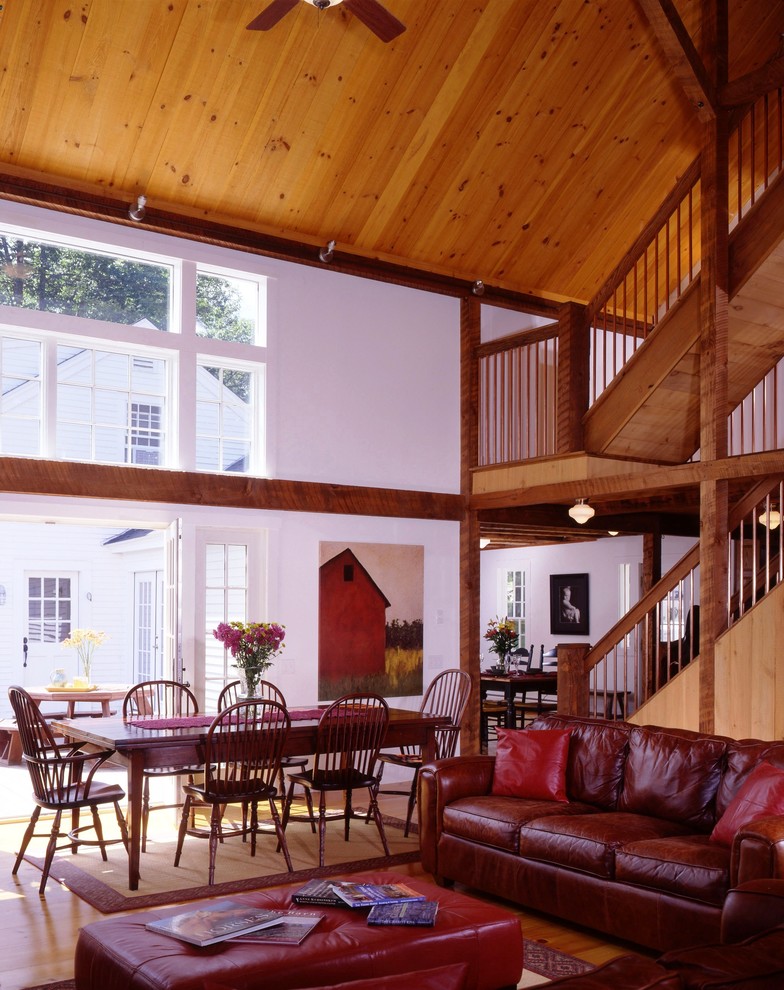 Exemple d'une grande salle de séjour mansardée ou avec mezzanine chic avec parquet clair, une cheminée standard et un manteau de cheminée en pierre.