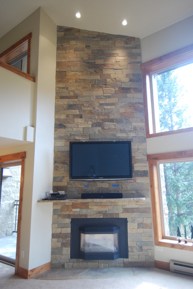 This is an example of a medium sized modern open plan games room in Denver with white walls, a standard fireplace, a stone fireplace surround and a wall mounted tv.