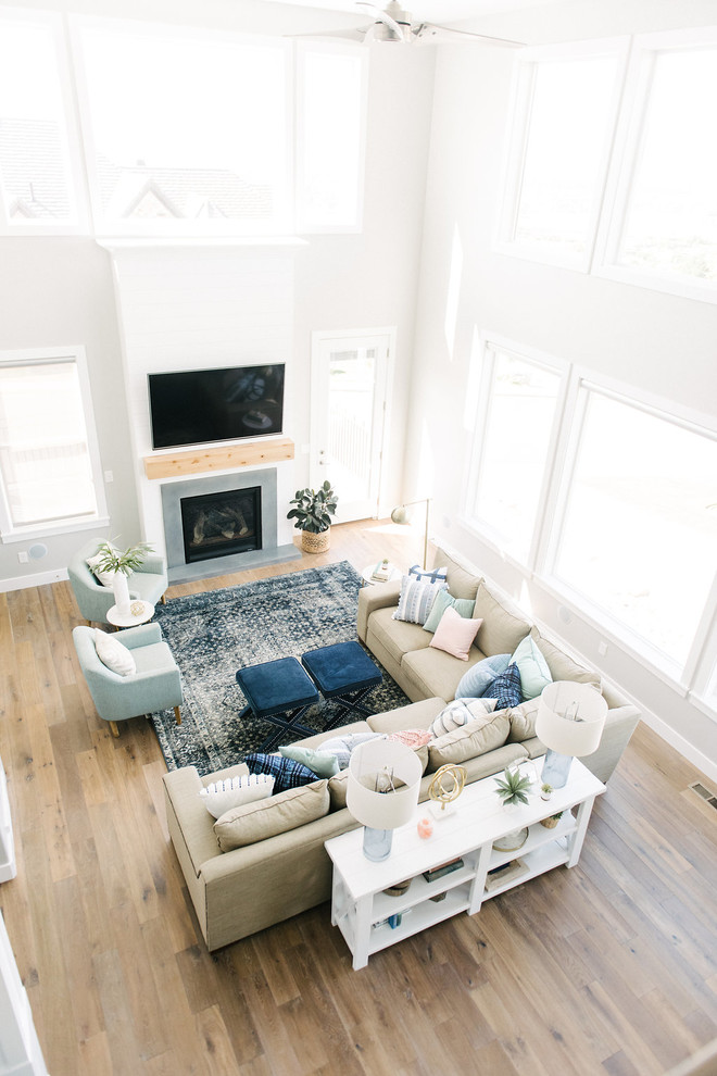 Ejemplo de sala de estar abierta tradicional renovada grande con paredes grises, suelo de madera en tonos medios, todas las chimeneas, marco de chimenea de hormigón y televisor colgado en la pared