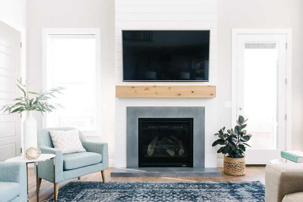 Foto de sala de estar abierta clásica renovada grande con paredes grises, suelo de madera en tonos medios, todas las chimeneas, marco de chimenea de hormigón y televisor colgado en la pared