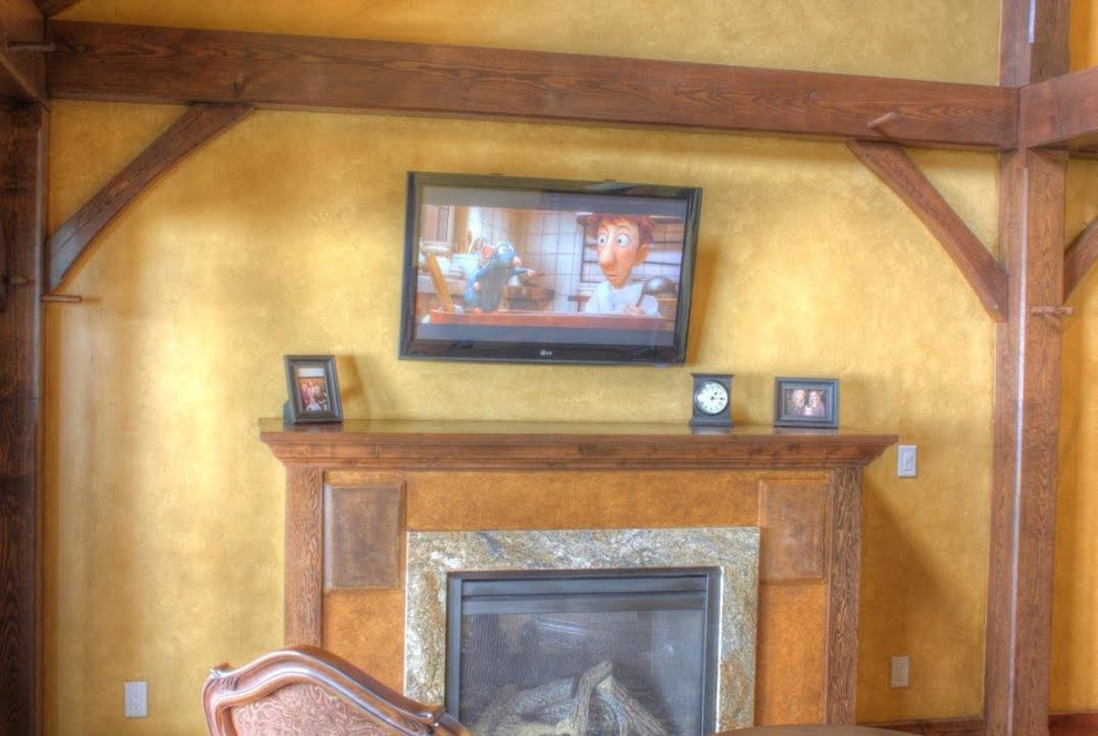 Стильный дизайн: открытая гостиная комната среднего размера в стиле рустика с желтыми стенами, стандартным камином, фасадом камина из дерева и телевизором на стене - последний тренд