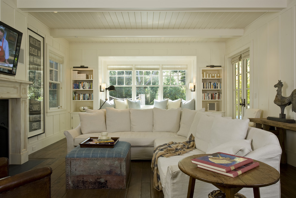 Exemple d'une salle de séjour chic avec un mur beige, une cheminée standard, un téléviseur fixé au mur et un manteau de cheminée en plâtre.