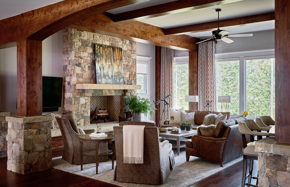 Offenes Rustikales Wohnzimmer mit grauer Wandfarbe, braunem Holzboden, Kamin, Kaminumrandung aus Stein und TV-Wand in Raleigh