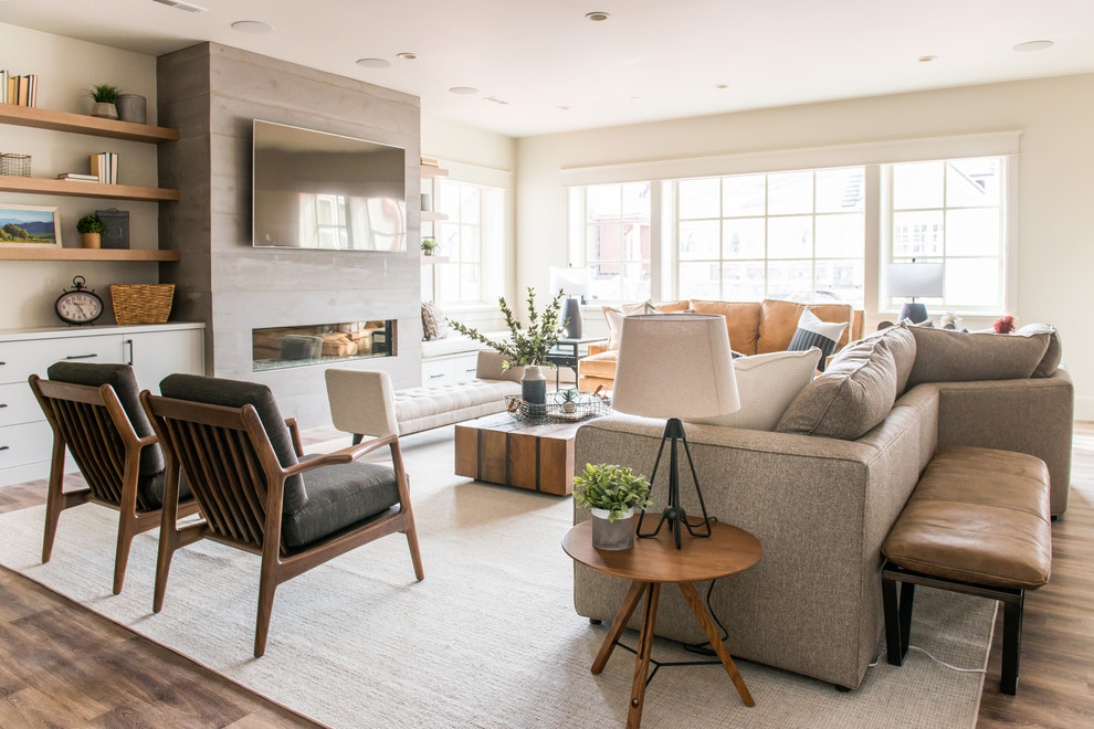 Imagen de sala de estar abierta clásica grande con paredes beige, suelo de madera en tonos medios, chimenea lineal, televisor colgado en la pared, suelo marrón y alfombra