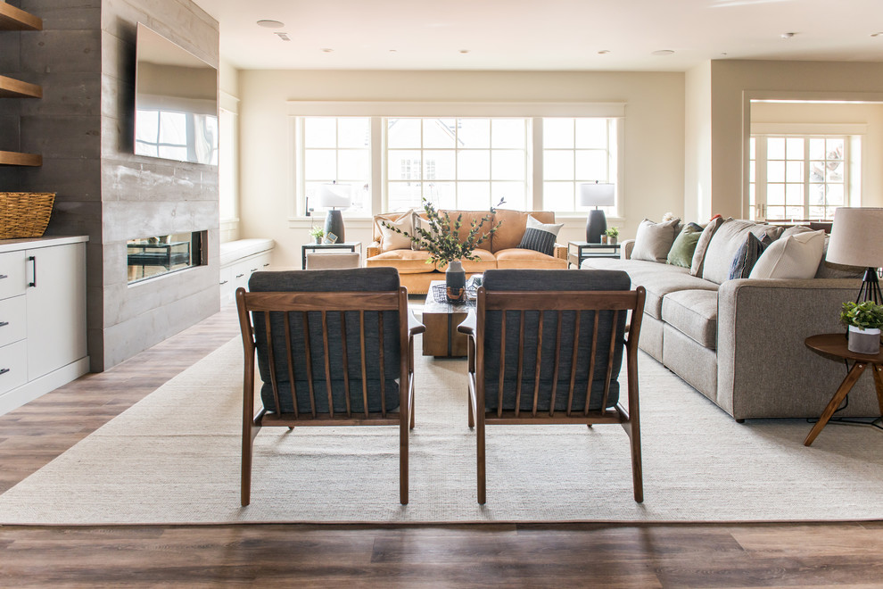 Diseño de sala de estar abierta clásica grande con paredes beige, suelo de madera en tonos medios, chimenea lineal, televisor colgado en la pared y suelo marrón