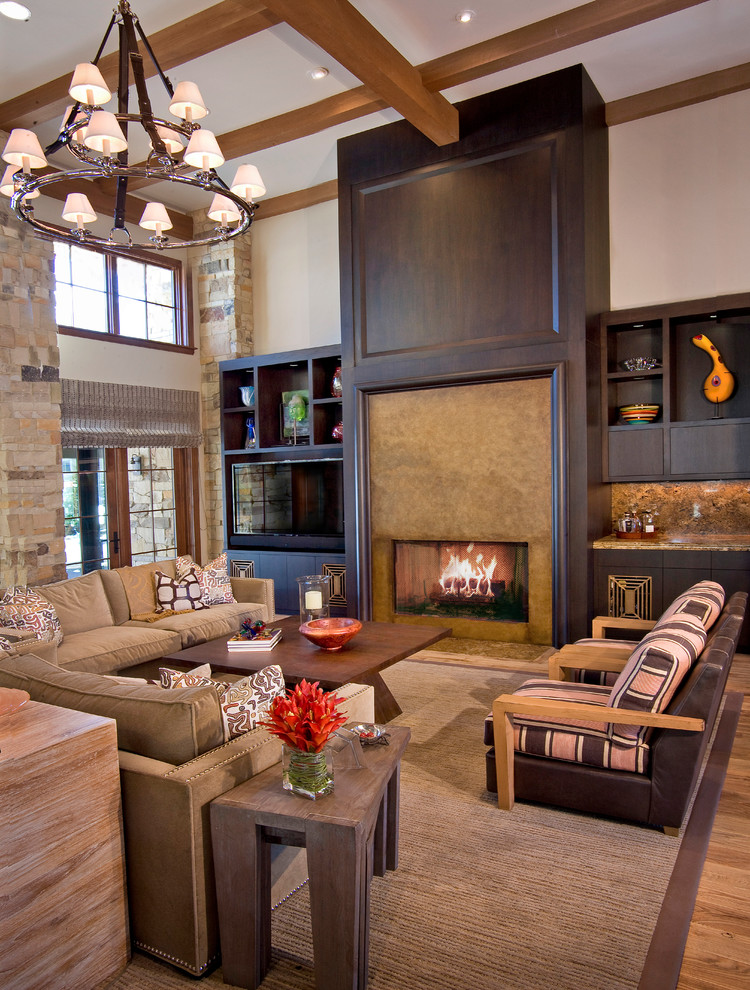 Cette image montre une grande salle de séjour design ouverte avec un bar de salon, un mur blanc, un sol en bois brun, une cheminée standard, un manteau de cheminée en pierre, un téléviseur fixé au mur et un sol marron.