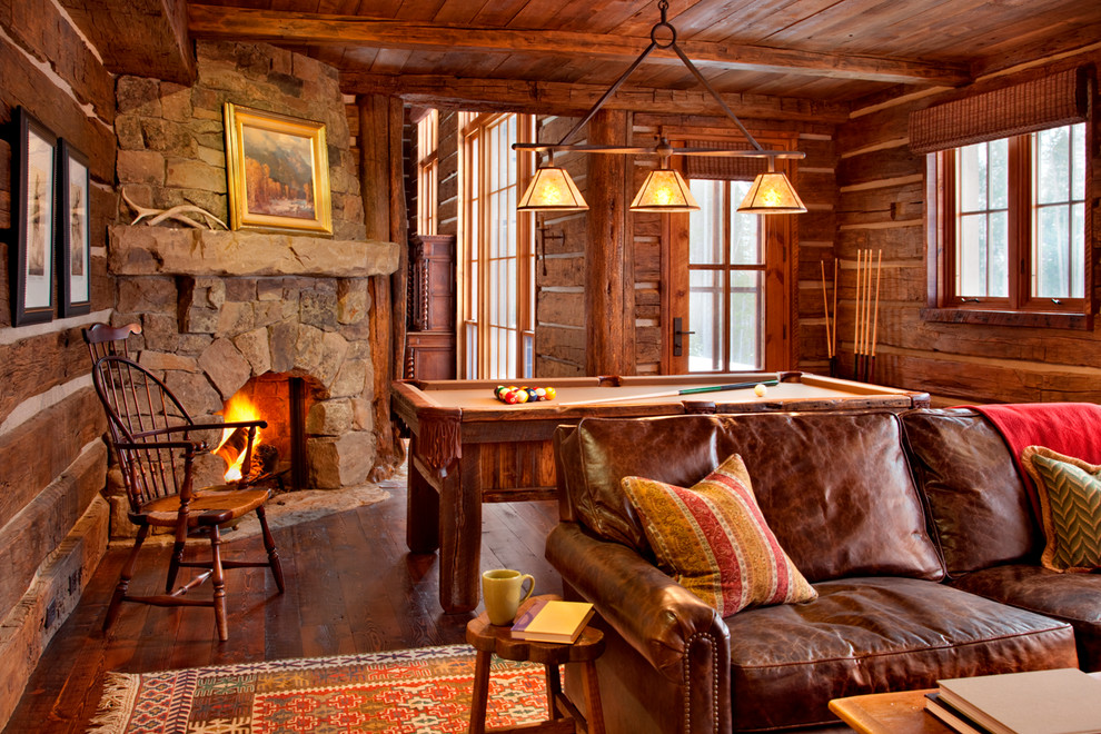 Imagen de sala de estar abierta rural de tamaño medio con suelo de madera en tonos medios, chimenea de esquina y marco de chimenea de piedra