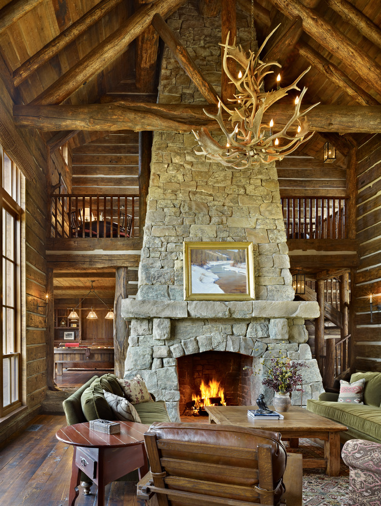 Idée de décoration pour une grande salle de séjour chalet ouverte avec un sol en bois brun, une cheminée standard et un manteau de cheminée en pierre.