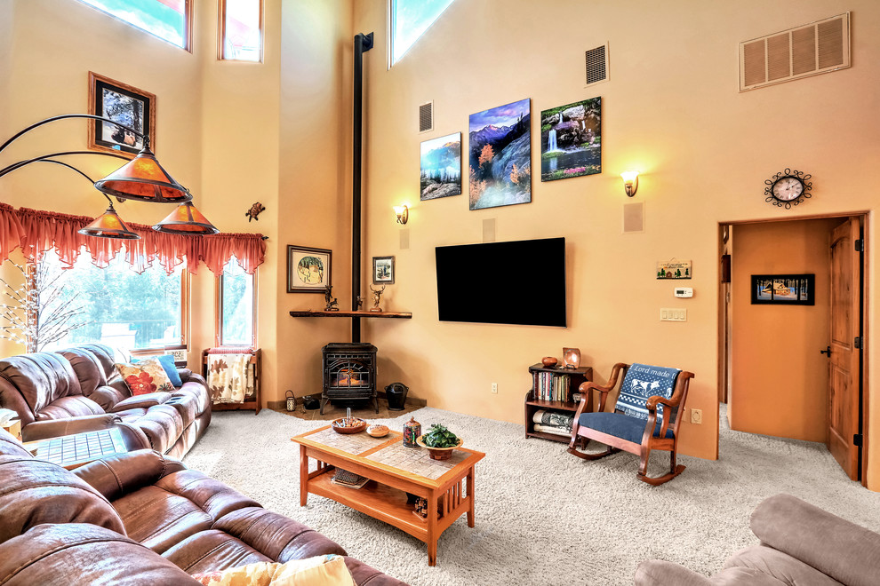 Idée de décoration pour une grande salle de séjour champêtre ouverte avec un mur beige, moquette, un poêle à bois, un téléviseur fixé au mur et un sol beige.